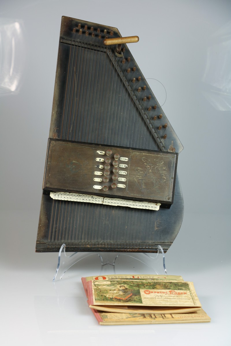 Een autoharp gemerkt: Müller's Accordzither Orpheus, met daarbij drie bijbehorende melodieboekjes, vol. 1, 3 en 4. met stemsleutel.