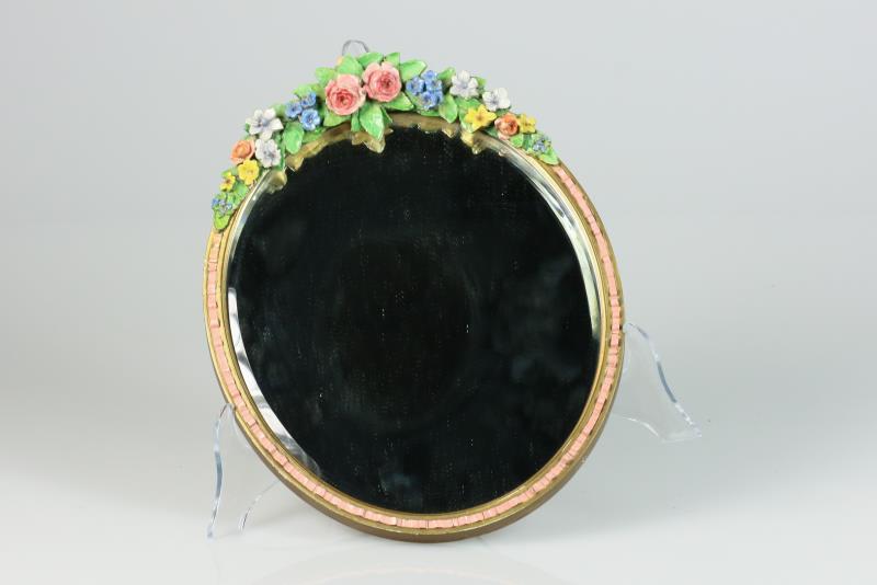 Een ovale spiegel versierd met aardewerk roosjes. Frankrijk, circa 1900.