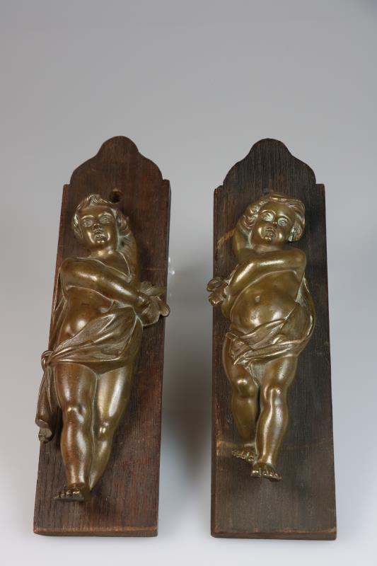 Twee bronzen putti, gemonteerd op paneeltjes, 1e helft 20e eeuw.