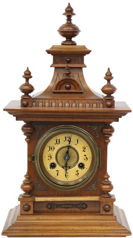 Een Engelse schouwpendule in eiken kast, Arabische cijferring, slagwerk op gongstaaf.