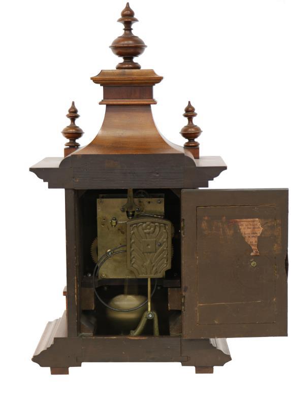 Een Engelse schouwpendule in eiken kast, Arabische cijferring, slagwerk op gongstaaf.