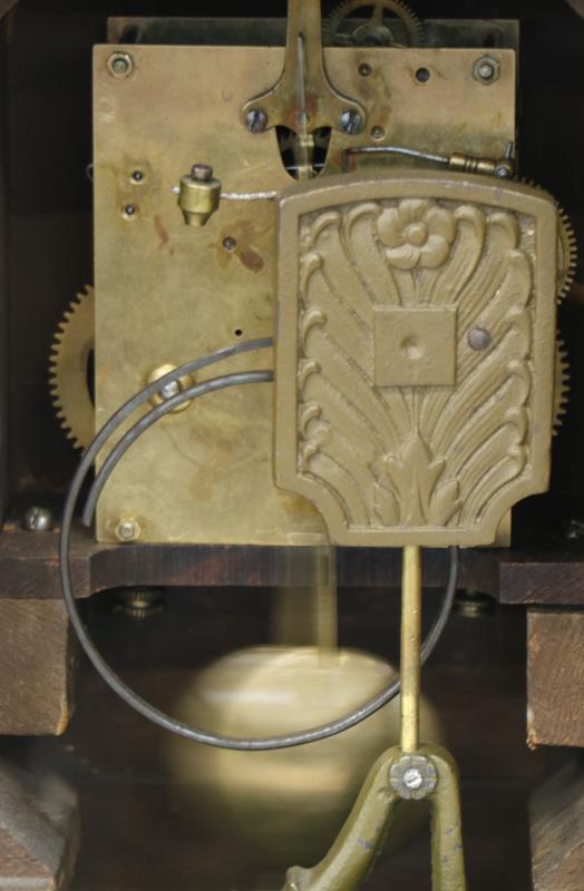 Een Engelse schouwpendule in eiken kast, Arabische cijferring, slagwerk op gongstaaf.