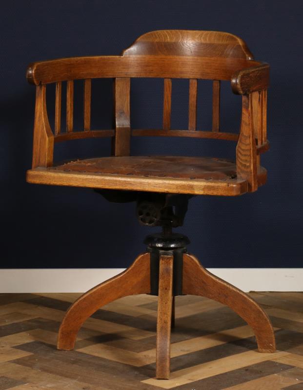 Een eikenhouten bureaustoel met open rugleuning, draaibaar en met leren zitting. Nederlands, 1e helft 20e eeuw. 