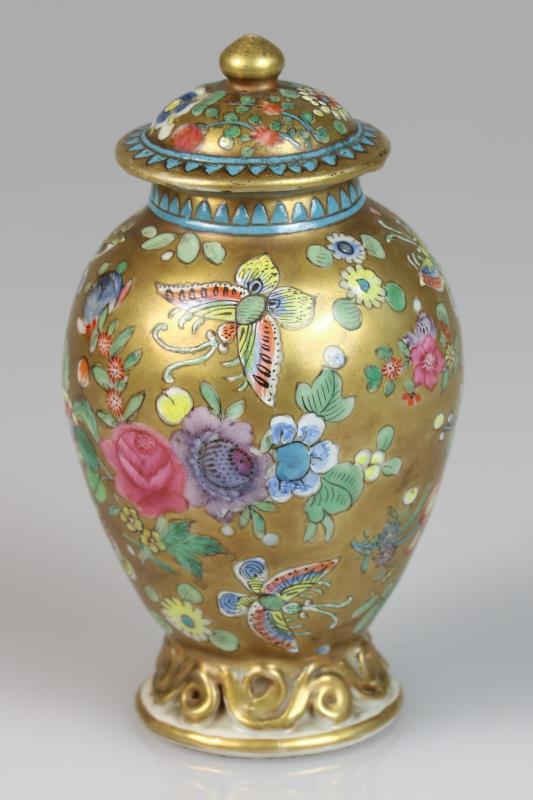 Een porseleinen theebus met floraal decor van vlinder en gouden fondkleur. China, 18e eeuw.