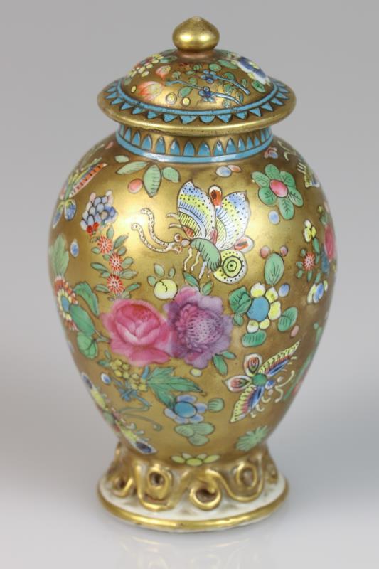 Een porseleinen theebus met floraal decor van vlinder en gouden fondkleur. China, 18e eeuw.