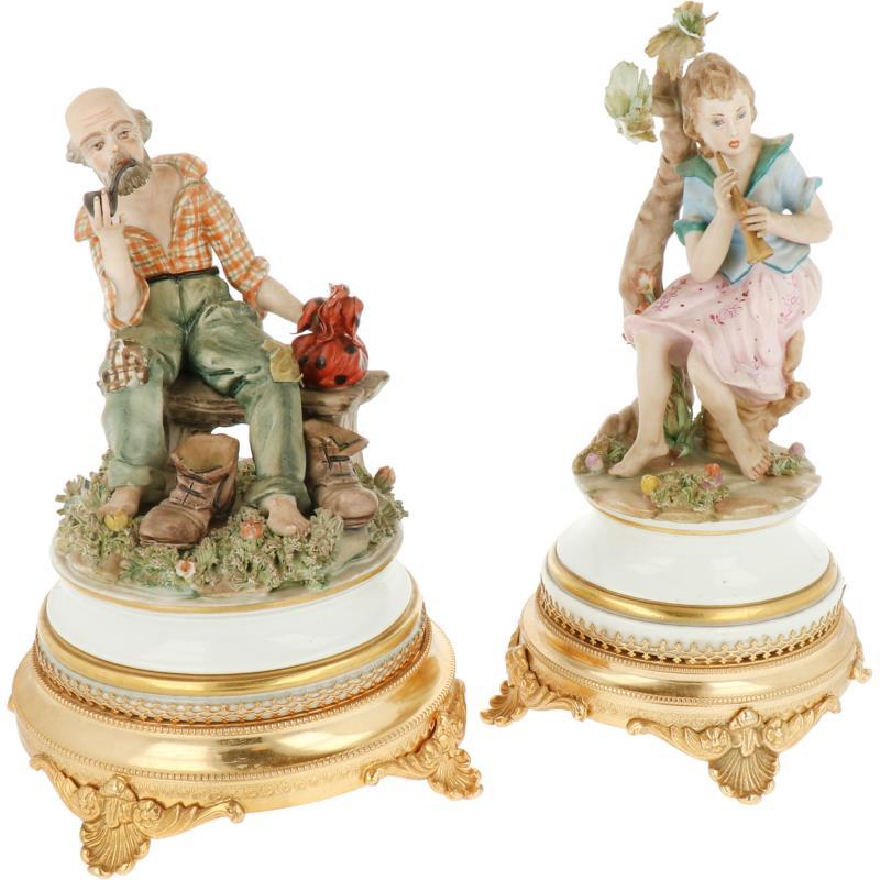 Een lot van (2) aardewerk groepjes voorstellend een rokende man en een muziekspelende vrouw. Capodimonte, 2e helft 20e eeuw.