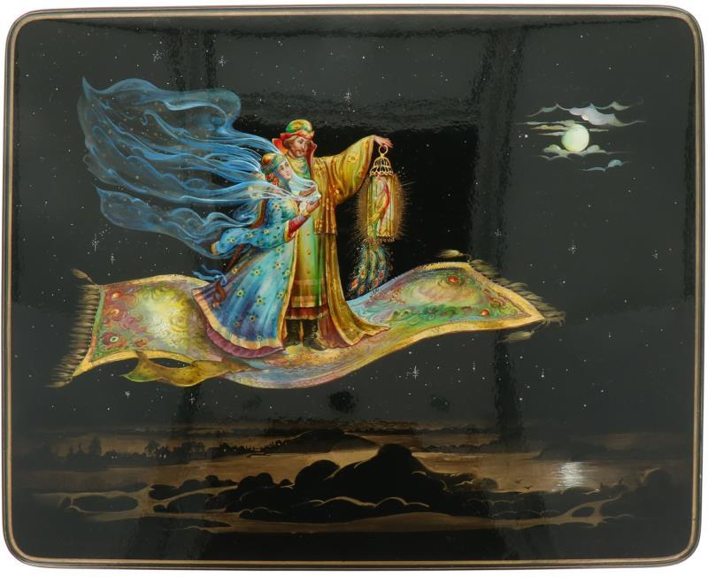 Een Russische lakdoos met voorstelling van twee figuren en een vogel op een vliegend tapijt. 