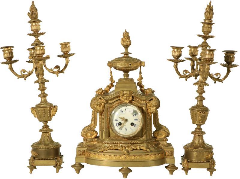 Een bronzen pendule met emaille wijzerplaat en twee bijbehorende kandelaren. Frankrijk, eind 19e eeuw.