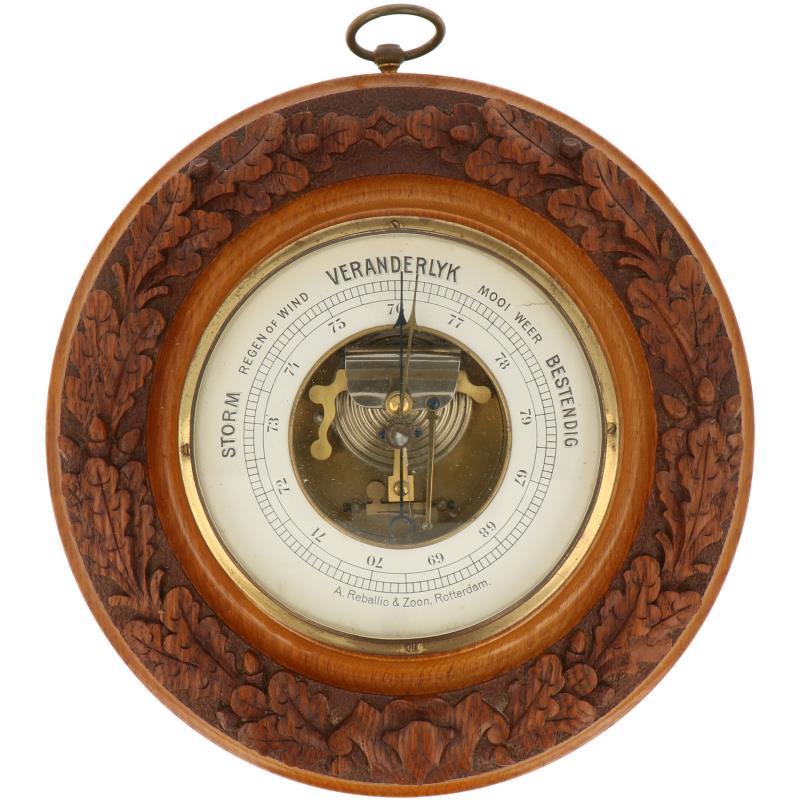 Een ronde barometer met snijwerk van eikenbladeren. Adres: A. Reballio & Zoon, Rotterdam. Ca. 1930.