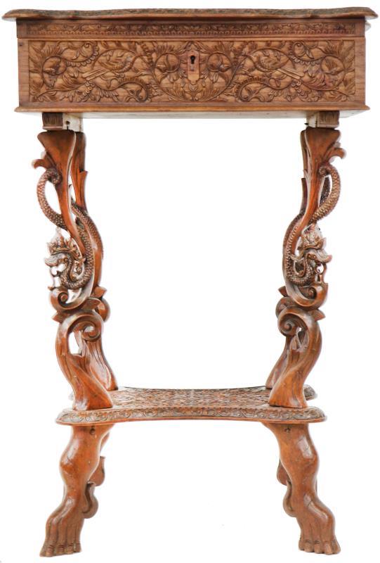Een koloniale houten naaitafel met rijk gesneden decors. Bali, begin 20e eeuw.