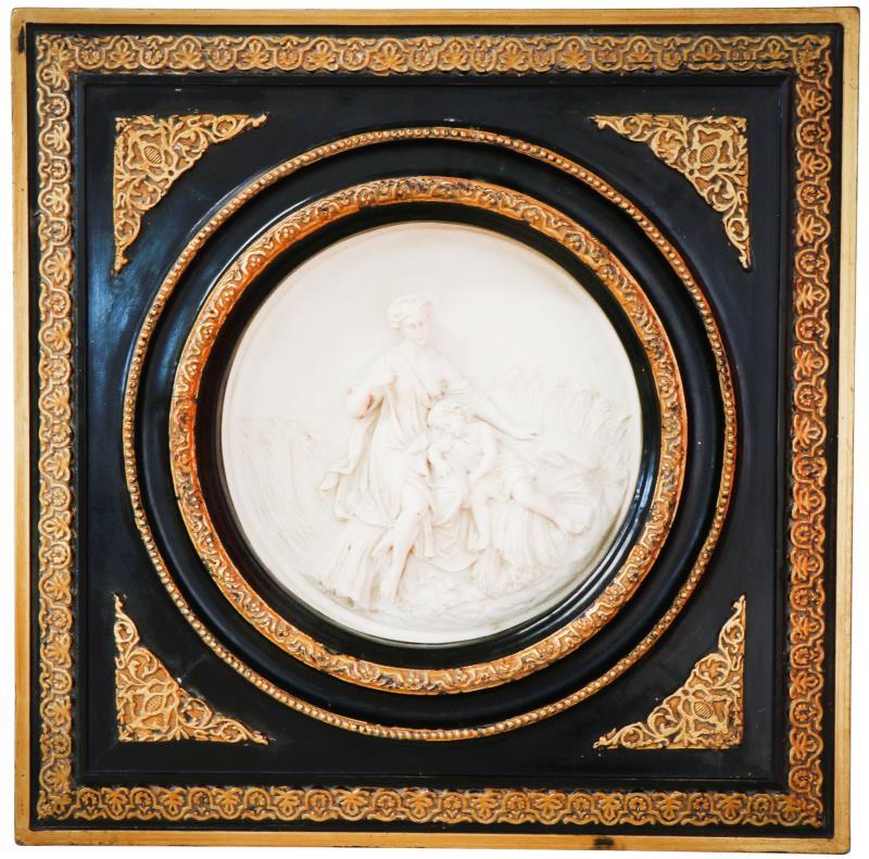 Een gietmarmeren plaquette met een 19e-eewse voorstelling van een moeder met kind in een korenveld. Op de achterzijde de penning van "Arts and Commerce". Diam.: 30 cm. 