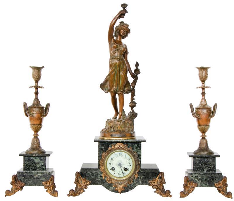 Een drie-delig ZAMAC klokkenstel met twee urnvormigel kandelaren en een figuur naar Joseph Barian: Rose Trémiere. Slagwerk met melodie incl. sleutel. 