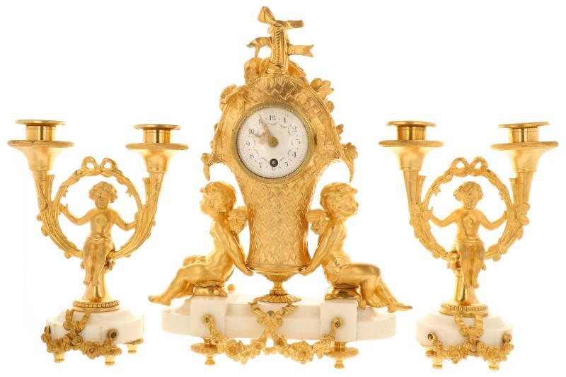Een vuurverguld klokkenstel met kandelaren, decor van zittende kindjes. Frankrijk, eind 19e eeuw.