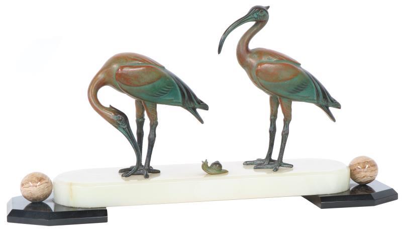 Een bronzen schouwstuk van twee Ibissen en een slak op een marmeren plint. 