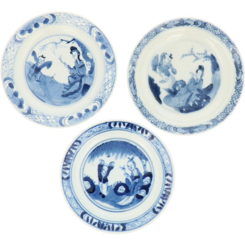 Een lot van drie porseleinen bordjes met decor van Lingzhi's en spelende Zotjes. China, Kangxi.