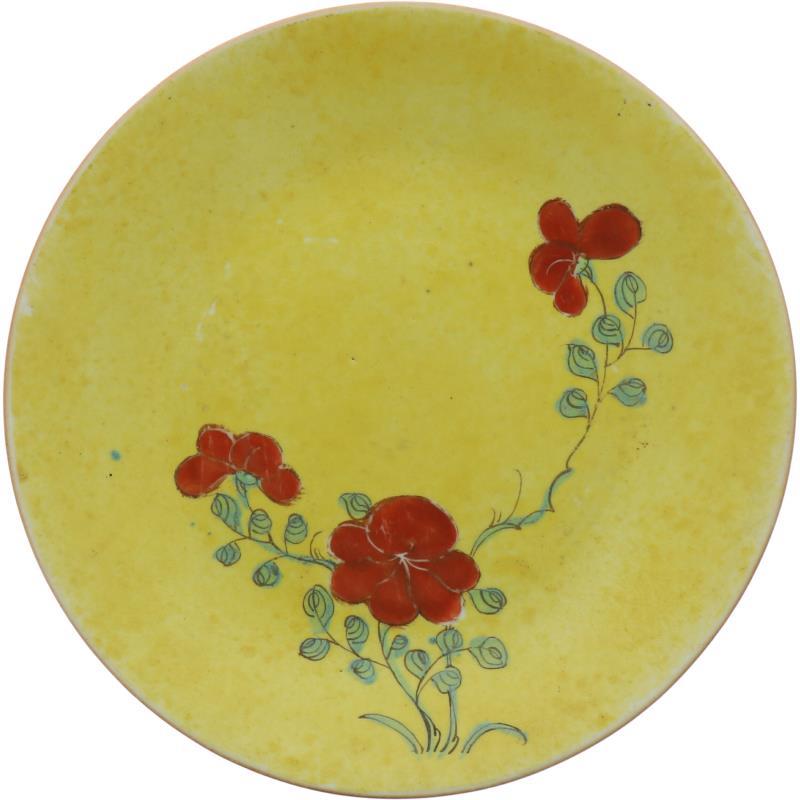 Een porseleinen bord met geel fond en beschildering van bloemen. China, 19e eeuw.