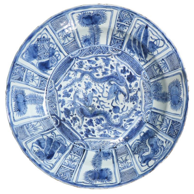Een kapitale porseleinen kraakschotel met blauw floraal decor in vakverdeling en draken decor in het centrum. China, Wanli.