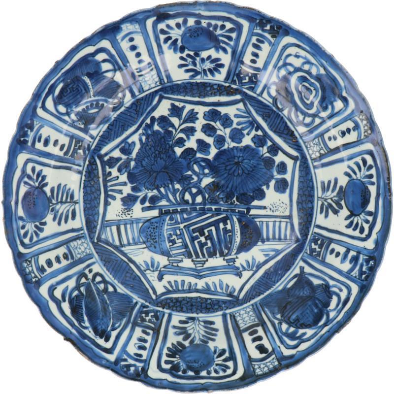 Een kraakporseleinen schotel met blauw decor van o.a een bloemenvaas. China, Wanli.