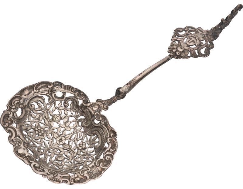 Strooilepel met ajour opengewerkte strooibak voorzien van fruit decoraties en op de steel een schild met medusa kop zilver.
