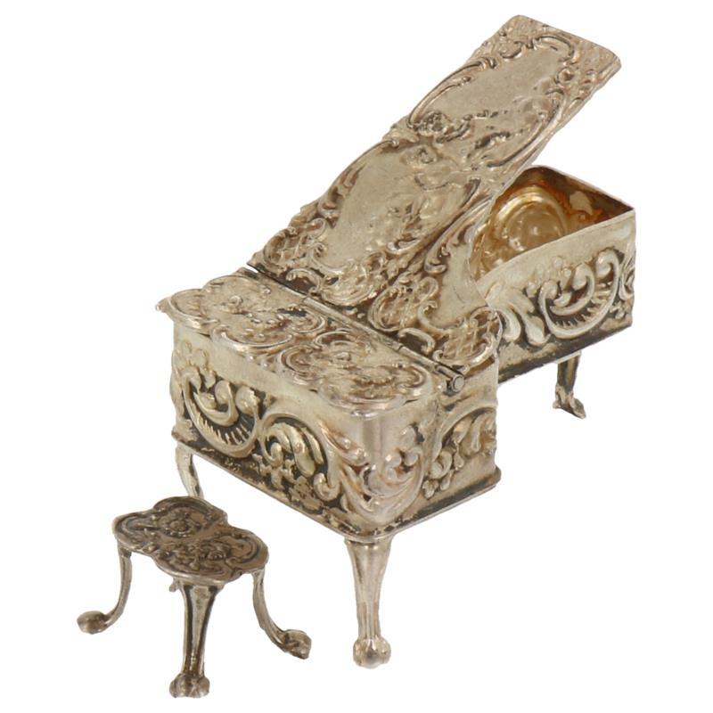 Miniatuur vleugelpiano met kruk bewerkt met rocailles en putti`s zilver.