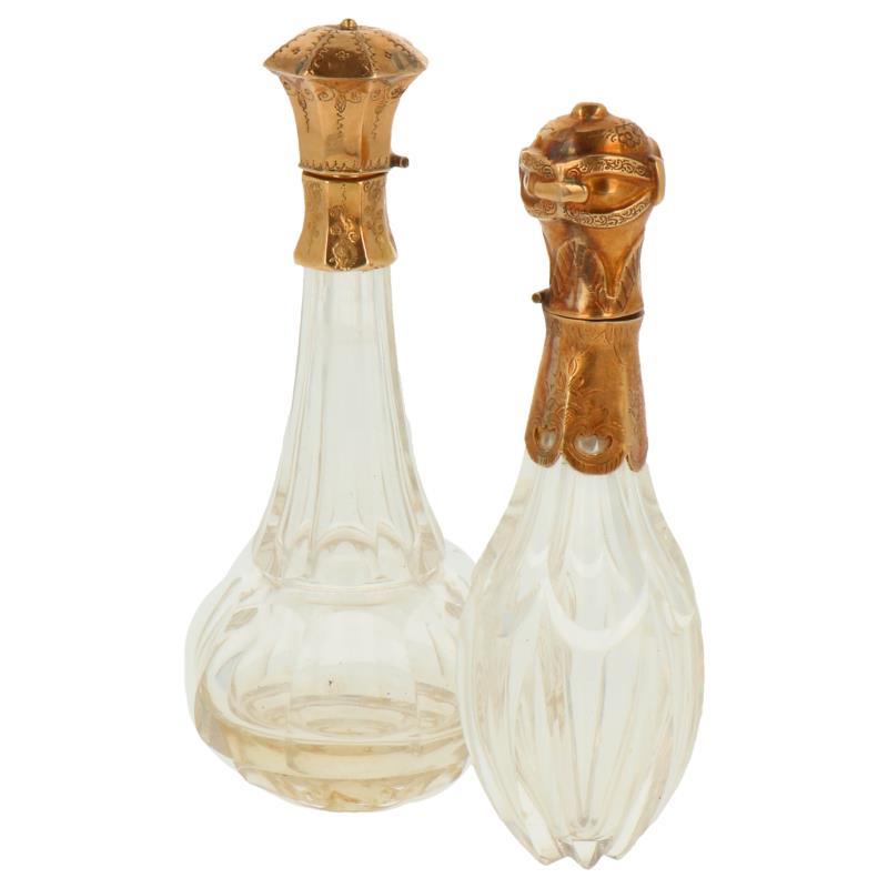 (2) kristallen parfumflesjes met gouden dop waarvan 1 het voetje mist beide zonder stopper zilver.