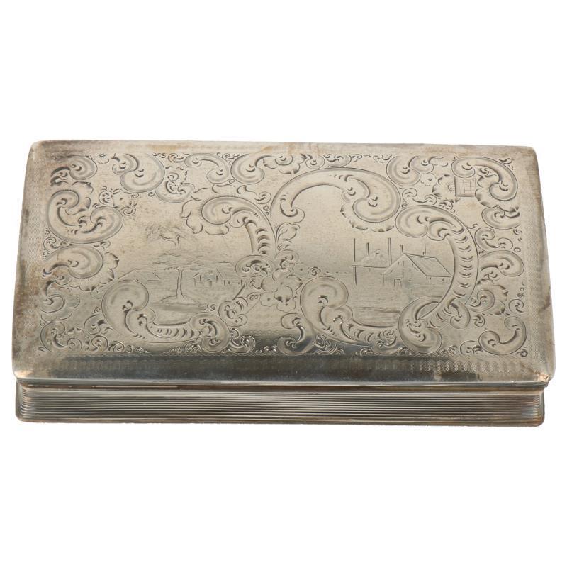 Tabaksdoos geribbeld model met aan bovenzijde hollands gegraveerd tafereel omringt doos rocaille versieringen zilver.
