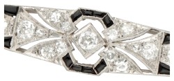 Platina Art Deco staafbroche bezet met ca. 0.70 ct. diamant en onyx.