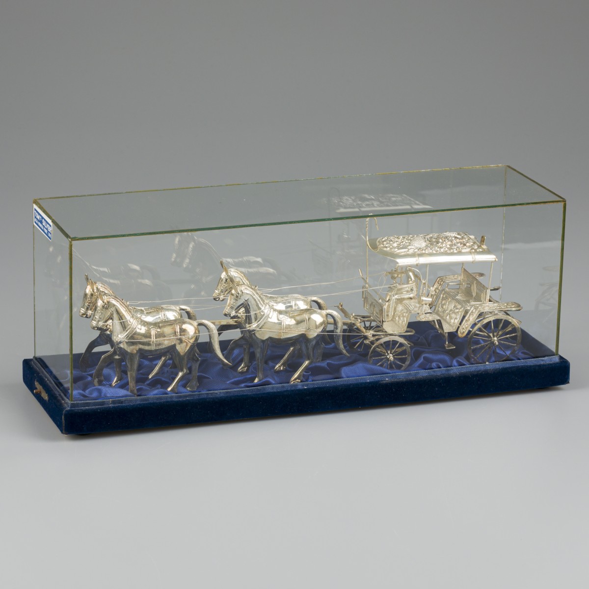 Miniatuur koets met paarden in vitrine, zilver.