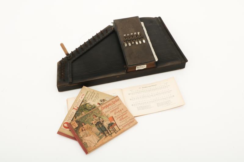 Een autoharp gemerkt: Müller's Accordzither Orpheus, met daarbij drie bijbehorende melodieboekjes, vol. 1, 3 en 4. met stemsleutel.