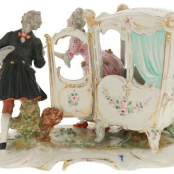 Een porseleinen groep voorstellende een man en vrouw bij een draagkoets. Ackermann & Fritze Völkstadt, Duitsland. 1e helft 20e eeuw.