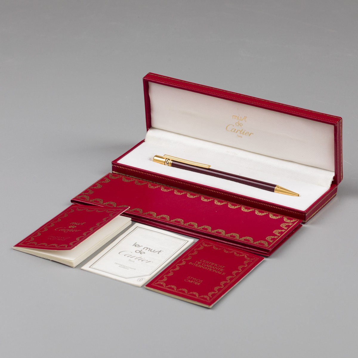 Must de Cartier Trinity balpen verguld, bordeauxrood Laque-de-Chine in marmerpatroon.