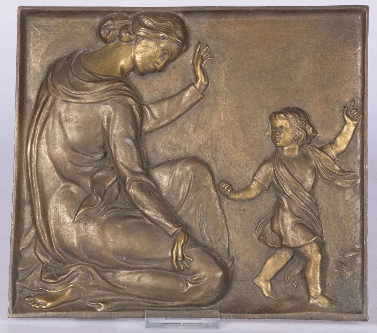 Een bronzen plaquette met voorstelling van moeder en kind.