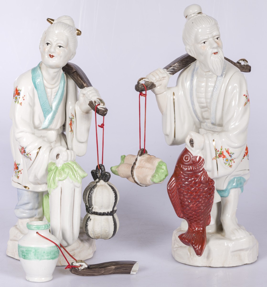 Een set van (2) porseleinen Aziatische figuren met juk op de schouders, 20e eeuw.