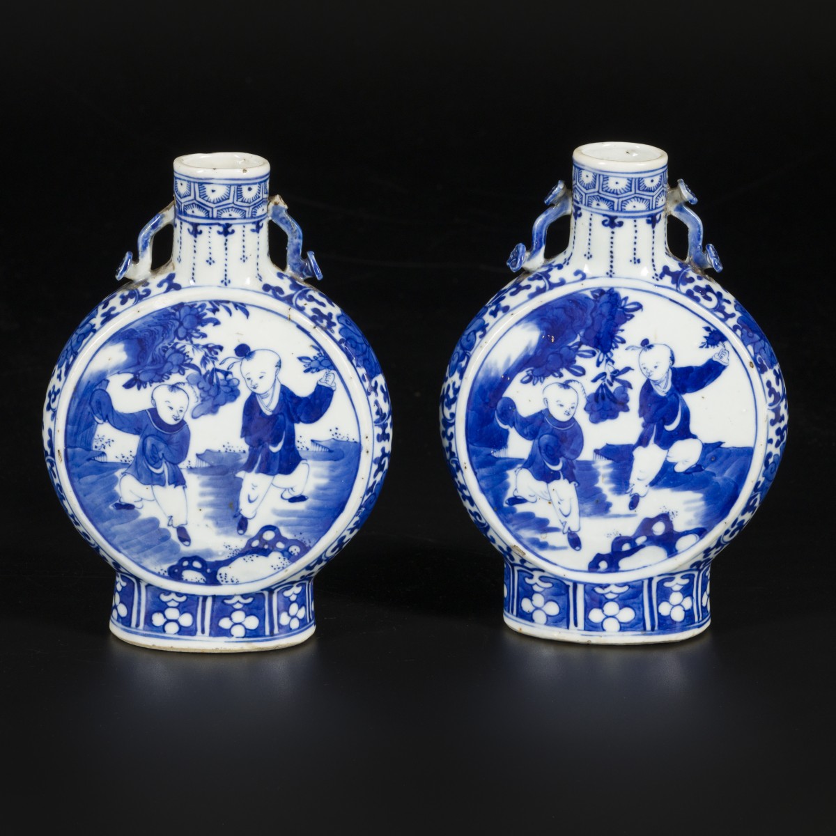 Een set van (2) porseleinen maanflessen gedecoreerd met spelende zotjes, gemerkt Kangxi, China, 19e eeuw.