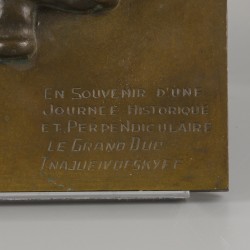 Een bronzen plaquette met voorstelling van een dansende kozak.