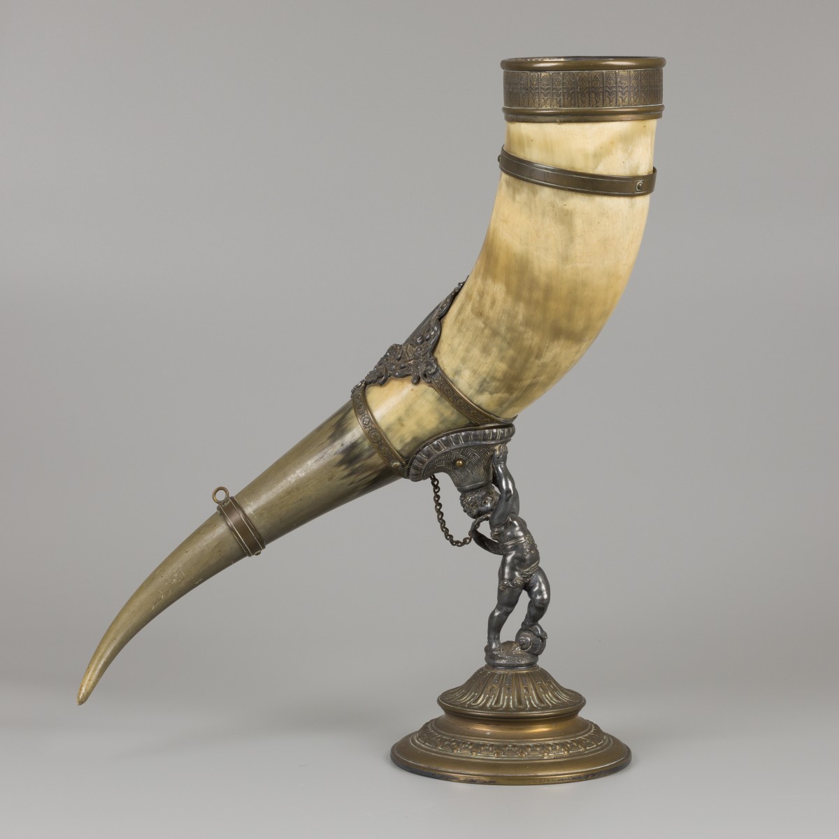 Een drinkhoorn vervaardigd van een ossenhoorn, gedragen door een putto, ca. 1920.