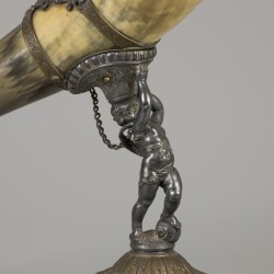 Een drinkhoorn vervaardigd van een ossenhoorn, gedragen door een putto, ca. 1920.