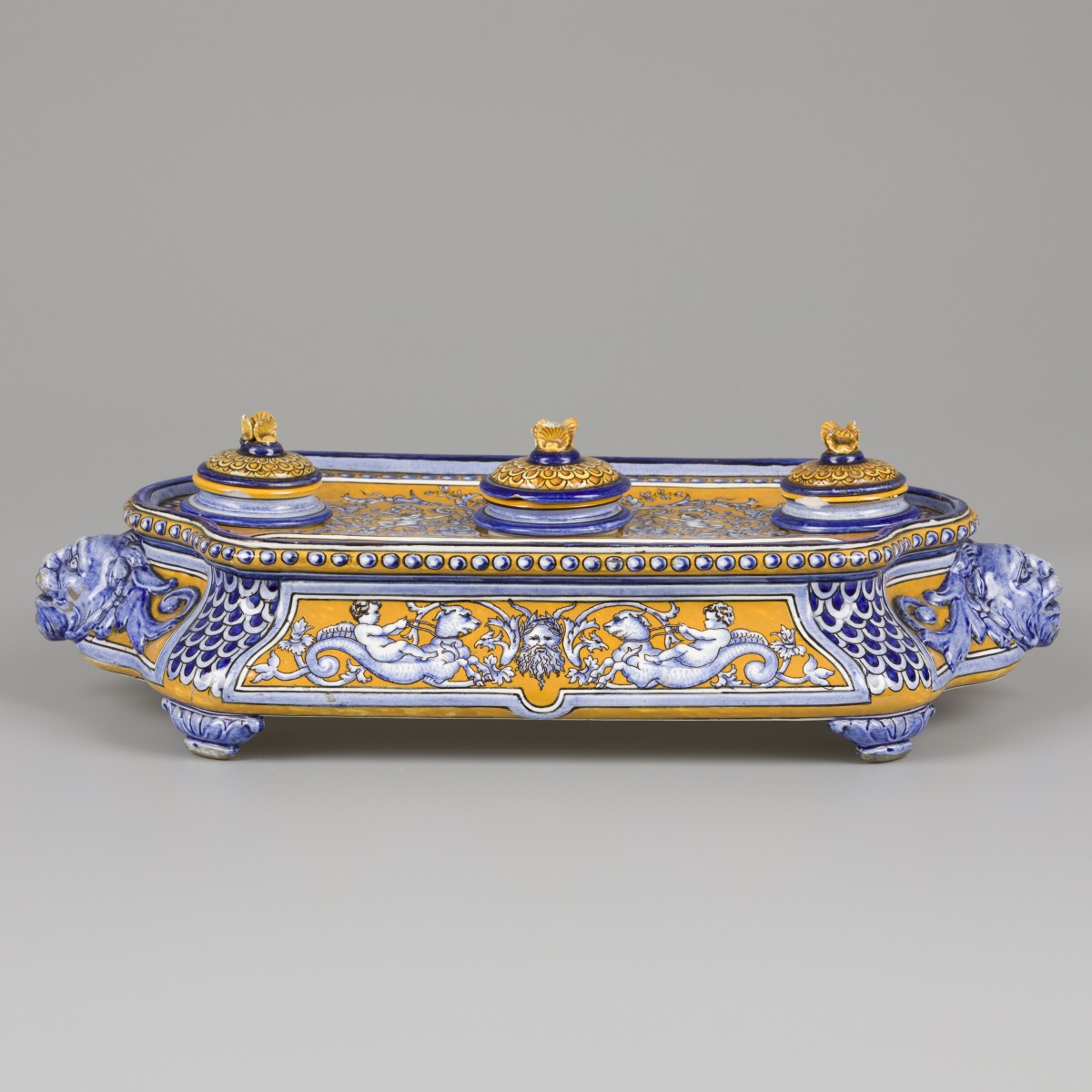 Een majolica inktstel gedecoreerd met putti gezeten op zeemonsters en diverse leeuwenmascarons, Italië, circa 1900.