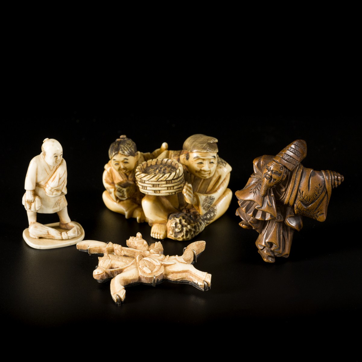 Een lot met (4) objecten voorstellende een broche van een strijder, (2) netsukes en een kleine okimono, einde Meiji periode.