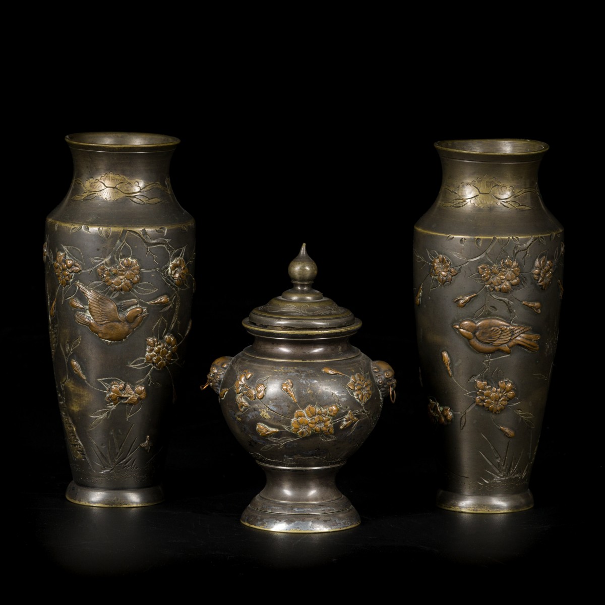 Een set van (3) Meiji bronzen vaasjes met reliëfdecor, twee balustervaasjes en een dekselpotje, Japan, eind 19e eeuw.