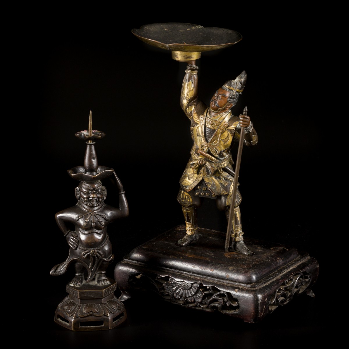 Een lot van (2) bronzen kandelaren waarvan één op houten voet, 19e/20e eeuw.