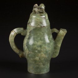 Een Celadon jade theepotje gedecoreerd met leeuw als dekselknop en reliëfdecor van een vogel en prunus. China, 19e eeuw.