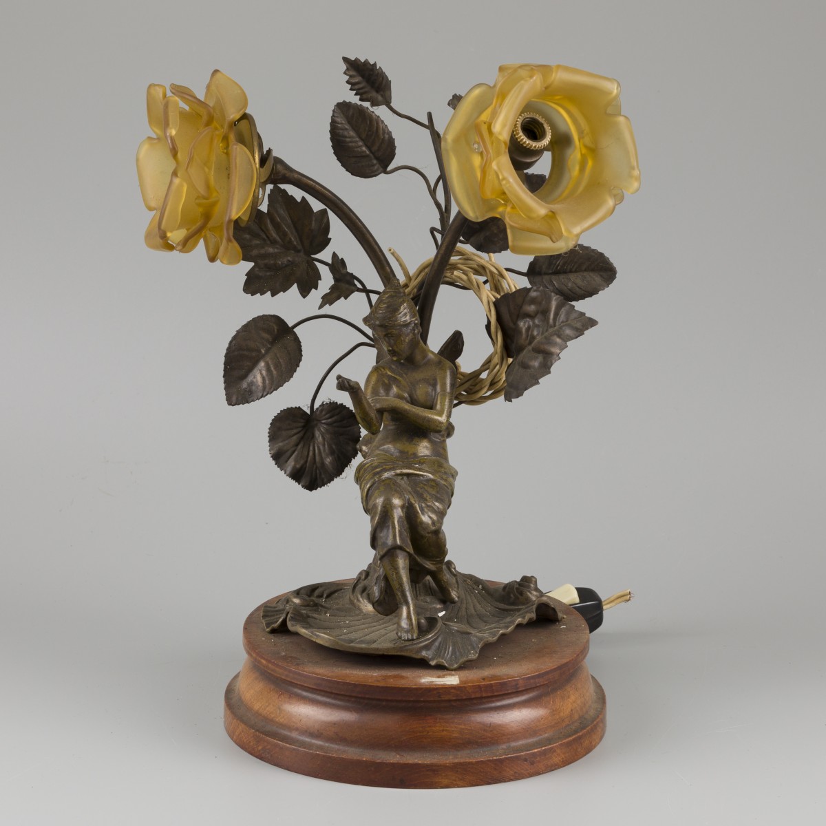 Een ZAMAK tafellamp van een jongedame rustend onder twee bloemen, 20e eeuw.