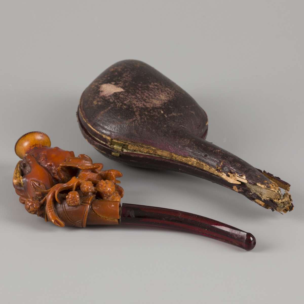 Een meerschuim pijpenkop in foudraal, een hand met drakenfruit, 19e eeuw.