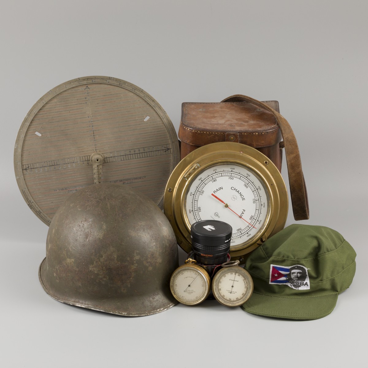 Een lot bestaande uit een Amerikaanse helm en Cubaanse pet, daarbij (2) handbarometer, een scheepsbarometer een foedraal en een lens, 20e eeuw.