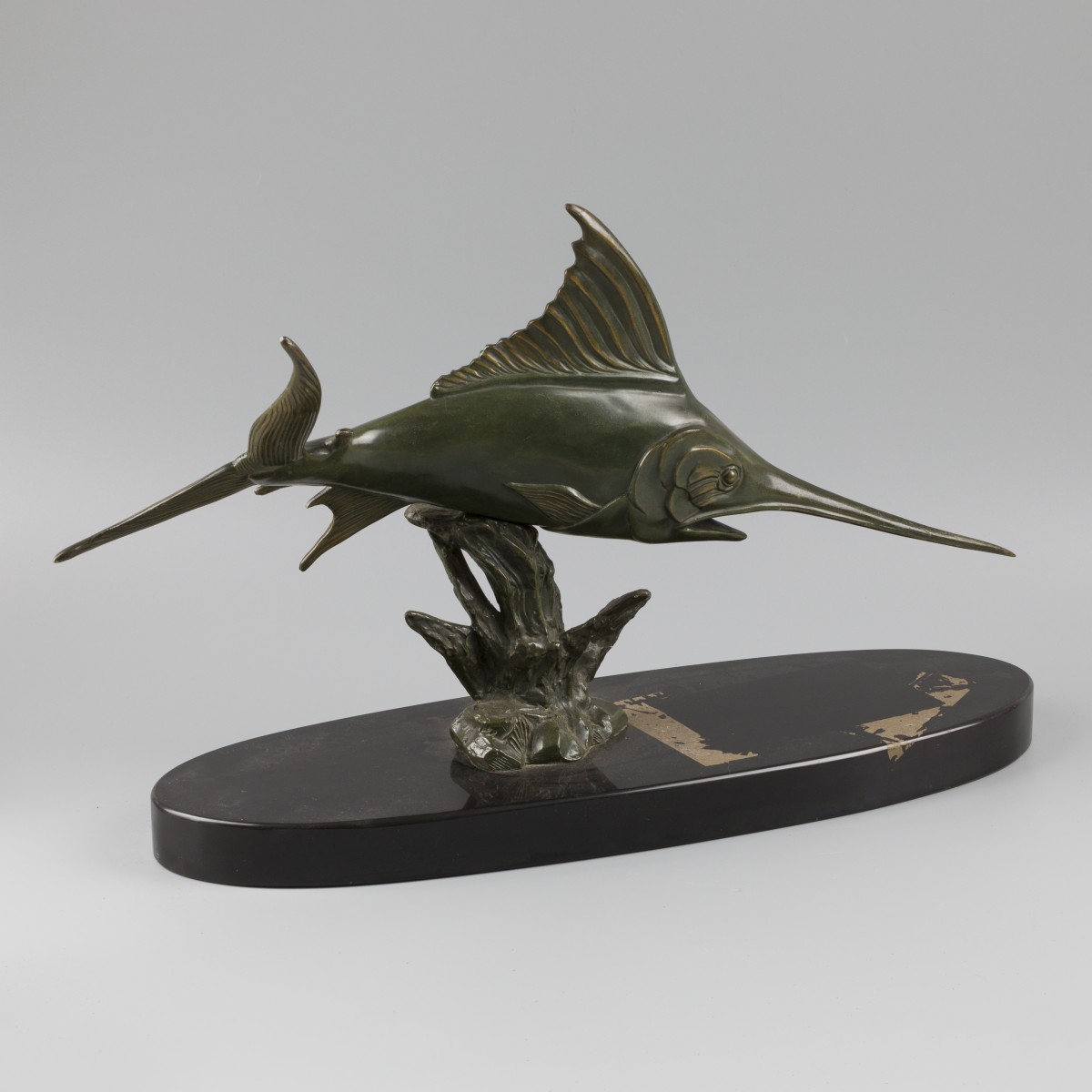 Een bronzen sierstuk in de vorm van een zeilvis.