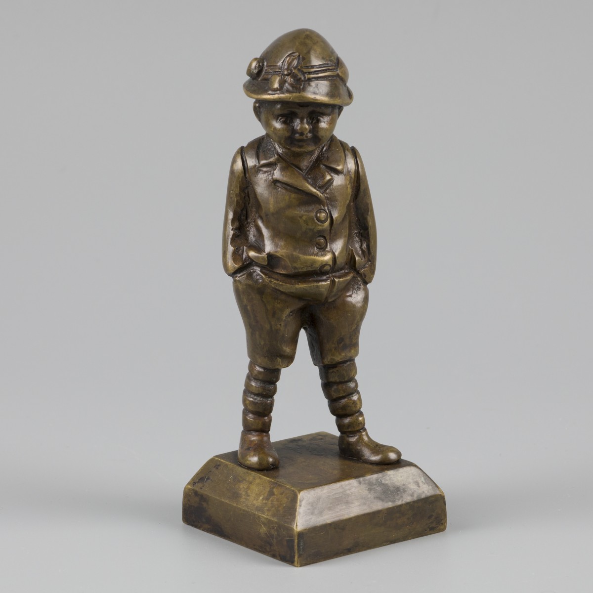 Een bronzen sculptuur van een peuter met de handen in de zakken, België, ca. 1920.