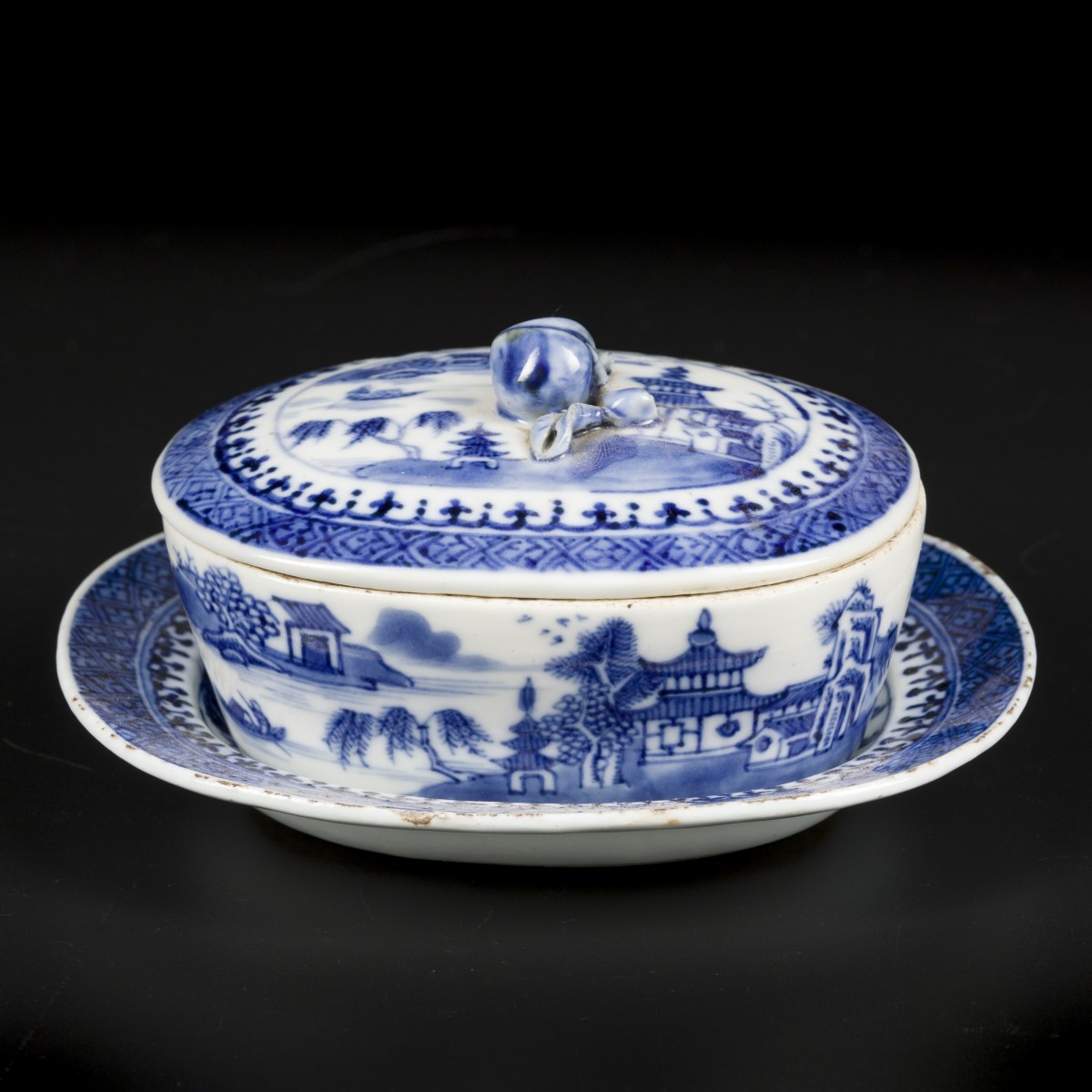 Een porseleinen ovale botervloot met onderschotel met rivierlandschap decor. China, Qianlong 18e eeuw.