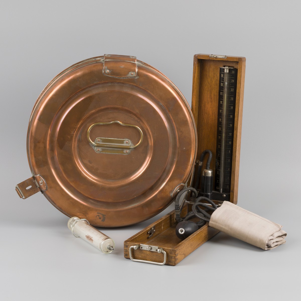 Een ronde messing sterilisatiedoos voor doktersinstrumenten met glazen spuit en bloeddrukmeter, medische instrumenten, 20e eeuw.