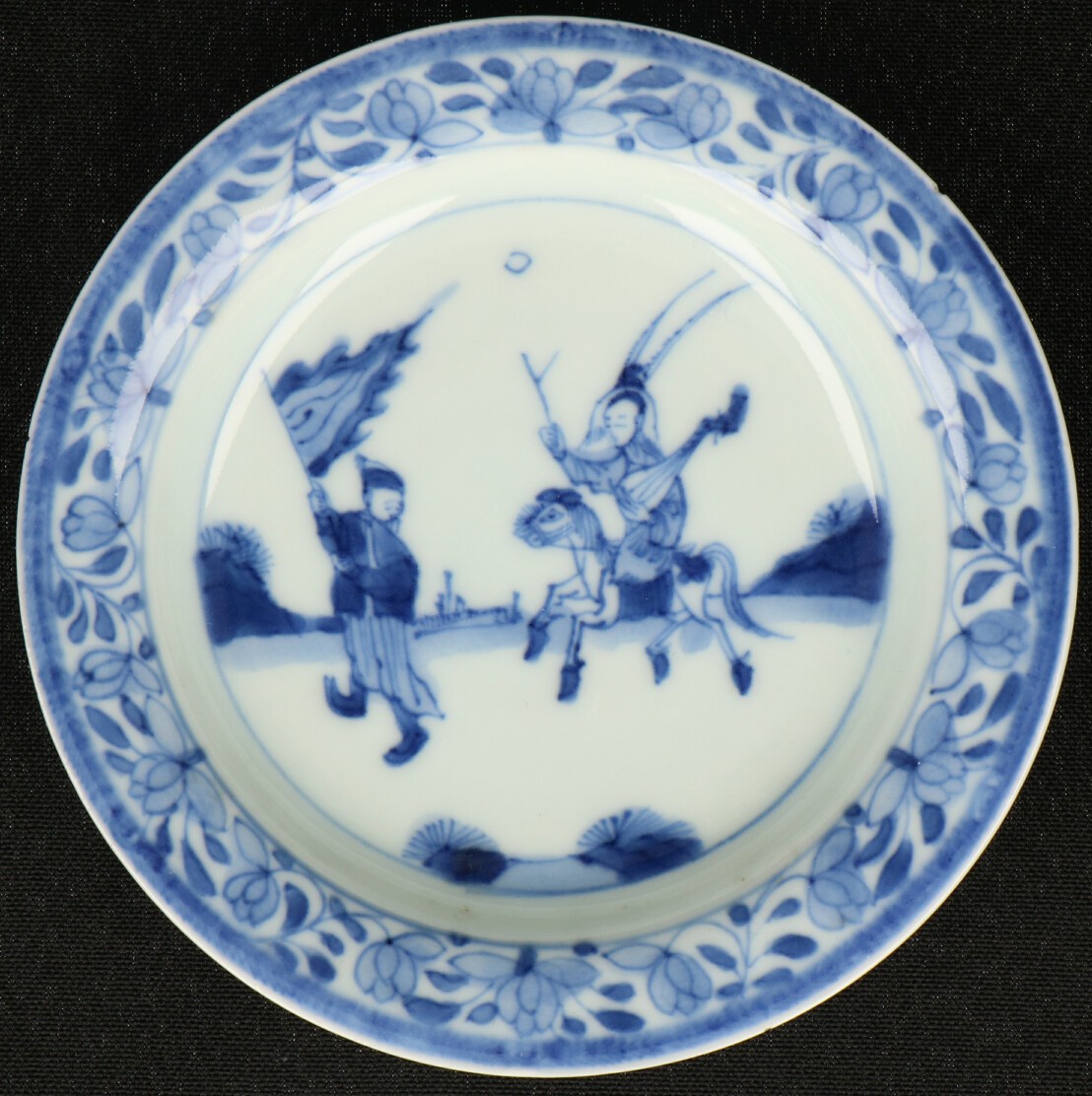 Een porseleinen schoteltje met ruiter en lansier decoratie. China, Kangxi.